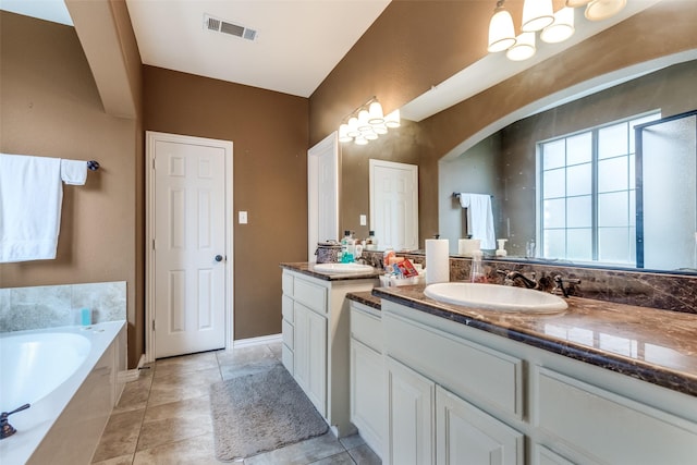 bathroom with tile patterned floors, vanity, and tiled bath