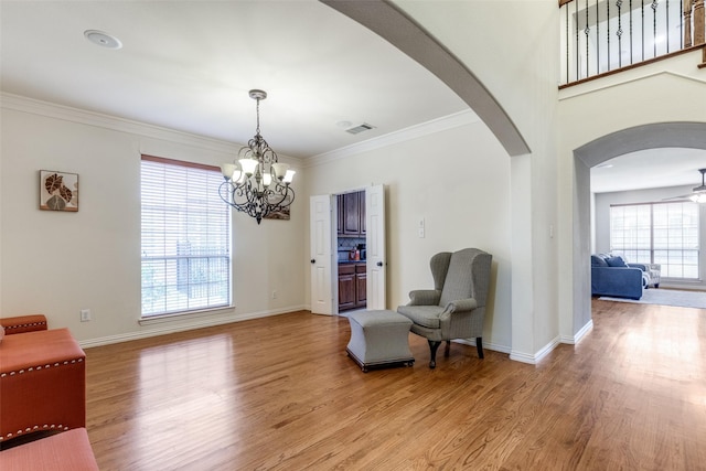 living area featuring crown molding, a chandelier, and light hardwood / wood-style flooring