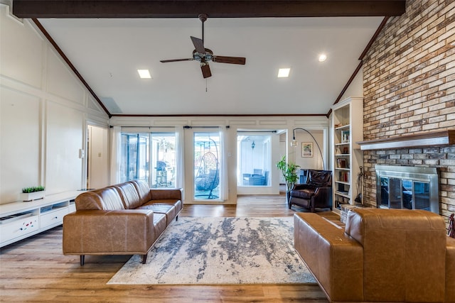 living room featuring crown molding, a fireplace, lofted ceiling with beams, and light hardwood / wood-style floors