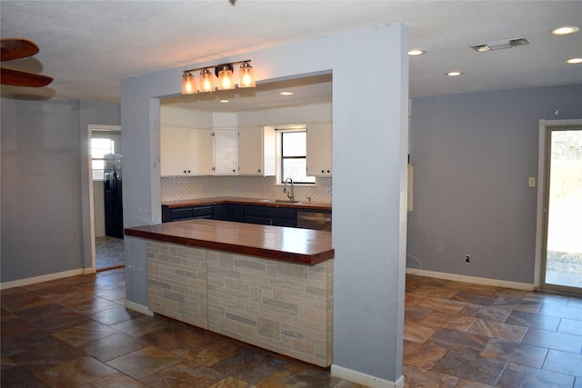 kitchen featuring tasteful backsplash, dishwasher, white cabinetry, sink, and wooden counters