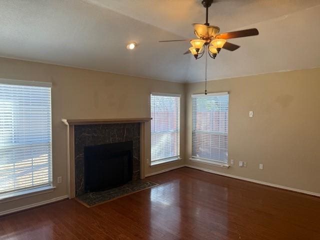 unfurnished living room with a premium fireplace, a wealth of natural light, dark hardwood / wood-style floors, and vaulted ceiling