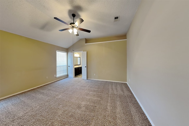 empty room with visible vents, light colored carpet, vaulted ceiling, a textured ceiling, and a ceiling fan