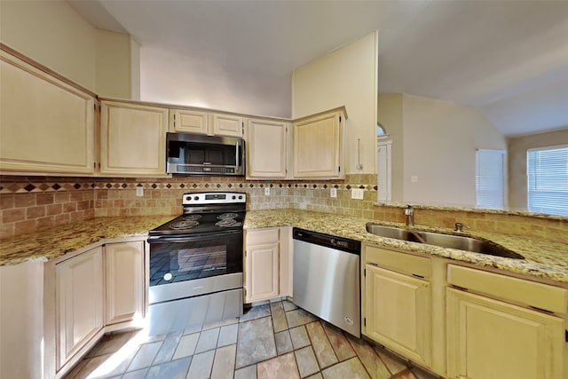 kitchen with appliances with stainless steel finishes, tasteful backsplash, sink, light stone counters, and cream cabinets