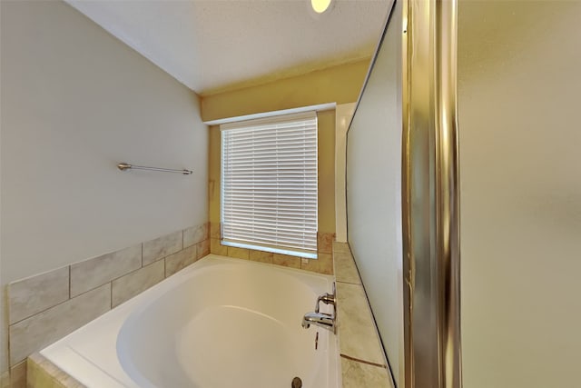 bathroom featuring tiled bath and a textured ceiling