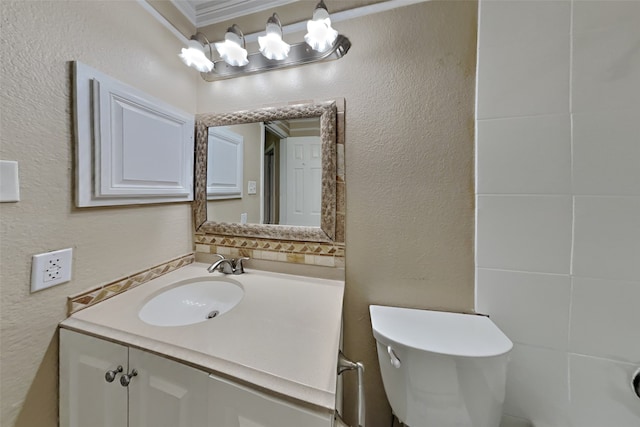 bathroom with vanity, toilet, and a textured wall