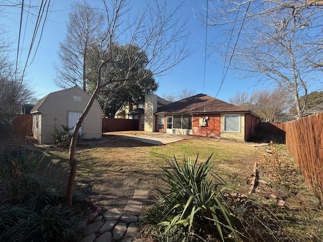 back of property with an outbuilding, a fenced backyard, and a patio area