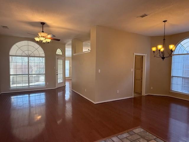 spare room with visible vents, baseboards, wood finished floors, and ceiling fan with notable chandelier