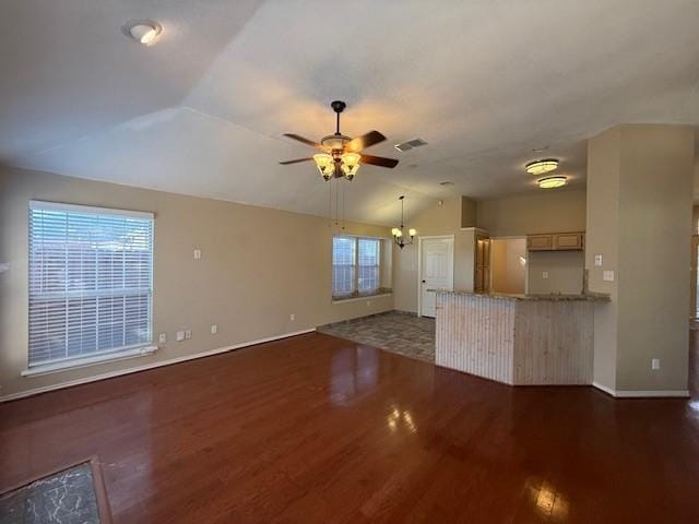 unfurnished living room featuring ceiling fan with notable chandelier, wood finished floors, visible vents, vaulted ceiling, and baseboards