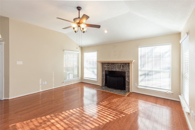 unfurnished living room featuring plenty of natural light, wood finished floors, a high end fireplace, and vaulted ceiling