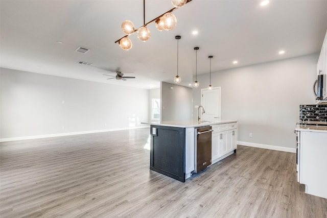 kitchen with ceiling fan, hanging light fixtures, an island with sink, white cabinets, and stainless steel dishwasher