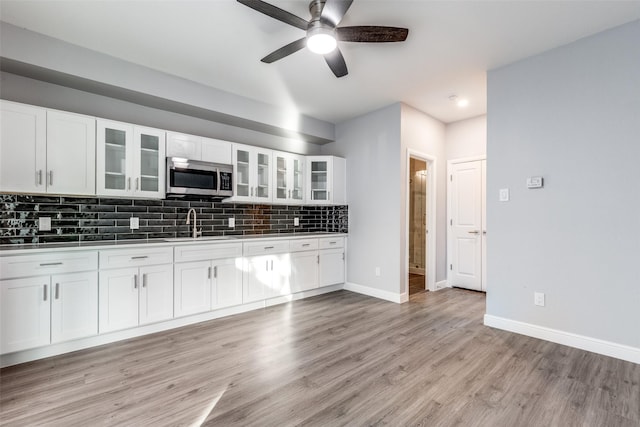 kitchen with backsplash, sink, light hardwood / wood-style floors, and white cabinets