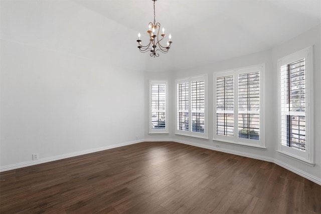 unfurnished room with a notable chandelier and dark hardwood / wood-style floors