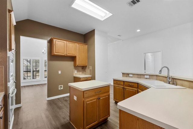 kitchen with sink, appliances with stainless steel finishes, a center island, dark hardwood / wood-style flooring, and vaulted ceiling