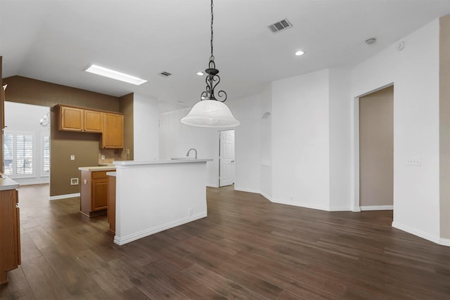 kitchen featuring a kitchen island with sink, decorative light fixtures, dark wood-type flooring, and lofted ceiling