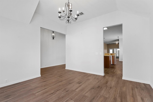 empty room featuring an inviting chandelier, dark wood-type flooring, and vaulted ceiling