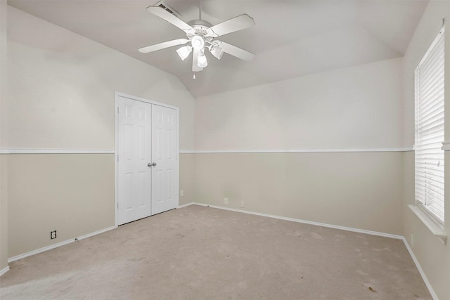 unfurnished bedroom featuring lofted ceiling, light colored carpet, a closet, and ceiling fan