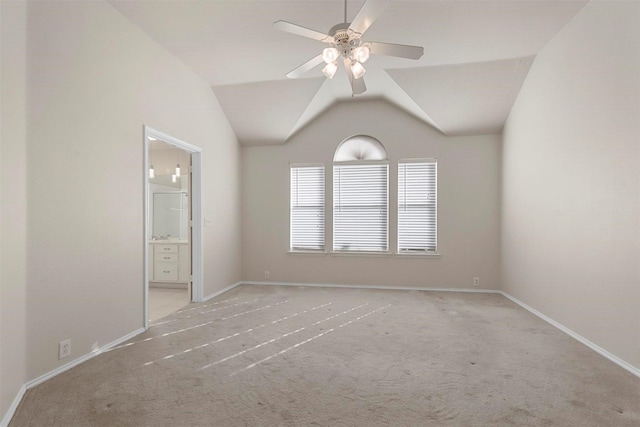 carpeted spare room featuring vaulted ceiling and ceiling fan