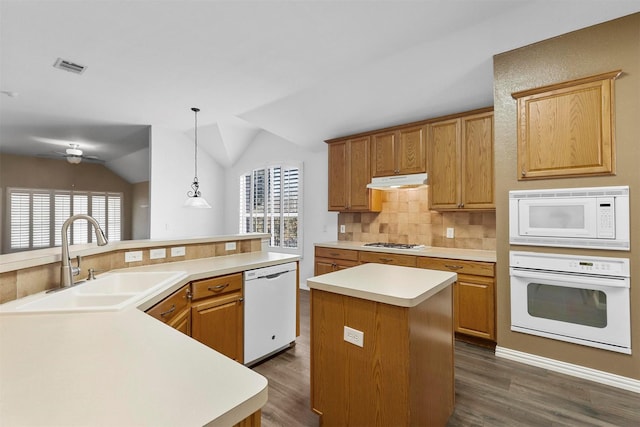 kitchen featuring pendant lighting, sink, white appliances, a center island, and a healthy amount of sunlight