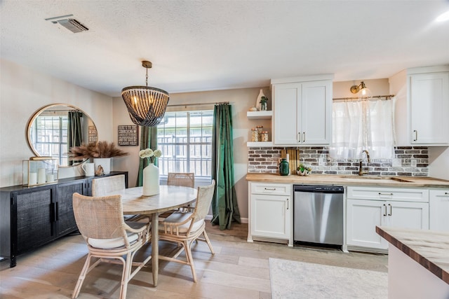 kitchen featuring pendant lighting, butcher block countertops, white cabinets, and dishwasher