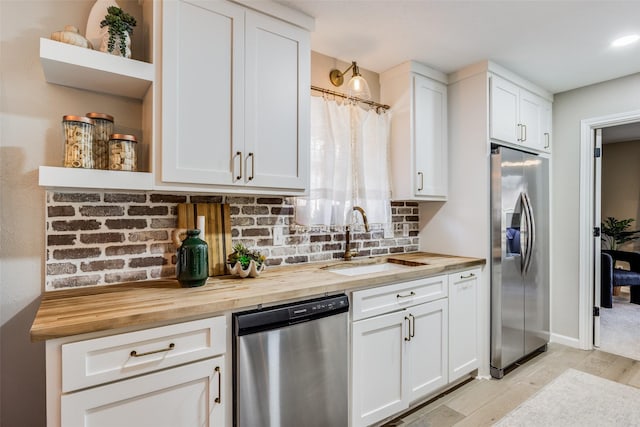 kitchen featuring white cabinets, appliances with stainless steel finishes, sink, and wooden counters