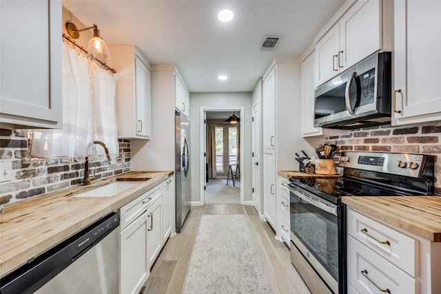 kitchen featuring white cabinetry, appliances with stainless steel finishes, sink, and wooden counters