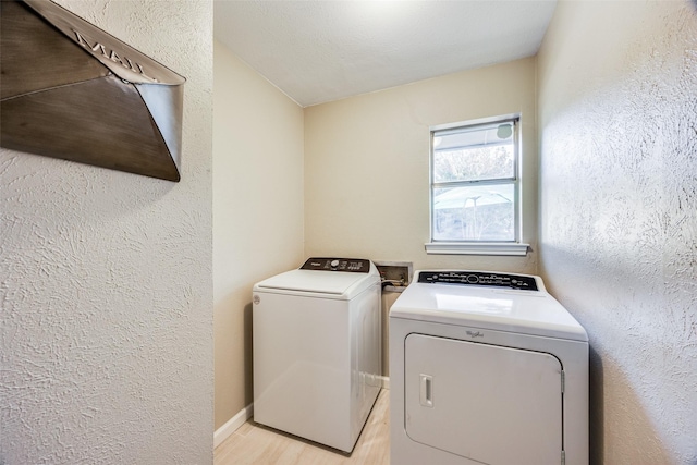 laundry room with washing machine and dryer and light wood-type flooring