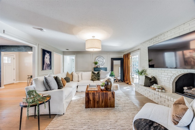 living room with a textured ceiling, light hardwood / wood-style floors, and a fireplace