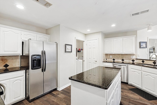 kitchen featuring white cabinetry, appliances with stainless steel finishes, washer and clothes dryer, and a kitchen island