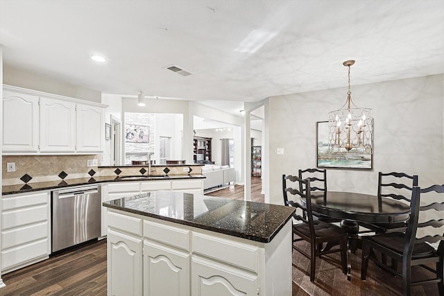 kitchen with a kitchen island, dark hardwood / wood-style floors, white cabinetry, dark stone countertops, and stainless steel dishwasher