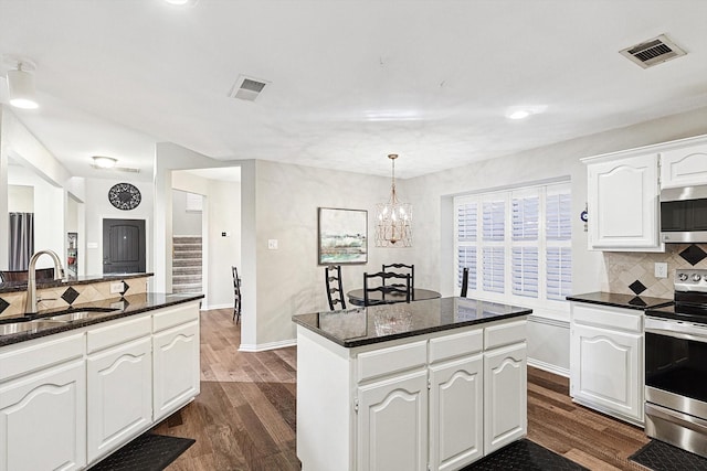 kitchen with pendant lighting, sink, appliances with stainless steel finishes, white cabinetry, and a kitchen island