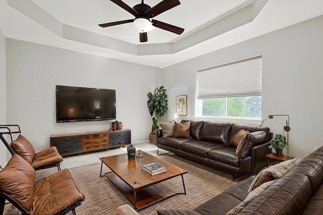 living room with ceiling fan and a tray ceiling