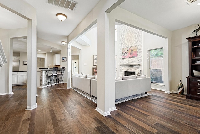 interior space featuring dark hardwood / wood-style flooring, a tiled fireplace, and ornate columns