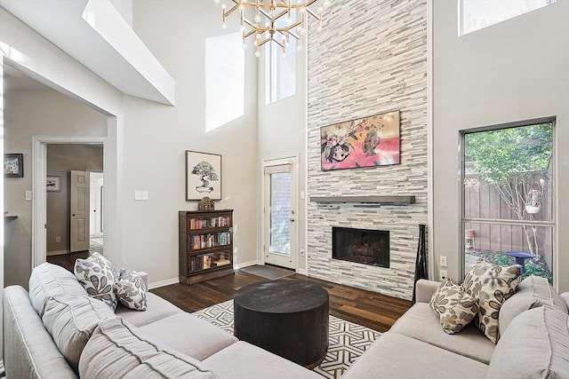 living room featuring a towering ceiling, a tile fireplace, dark hardwood / wood-style floors, and a chandelier