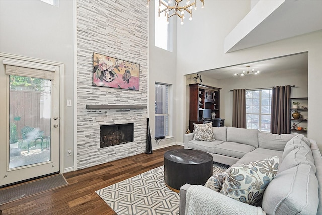 living room with an inviting chandelier, hardwood / wood-style flooring, a tile fireplace, and a towering ceiling