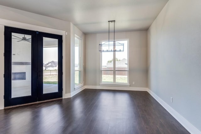 unfurnished dining area with dark hardwood / wood-style flooring, french doors, and a chandelier