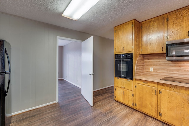 kitchen featuring dark hardwood / wood-style floors, a textured ceiling, and black appliances