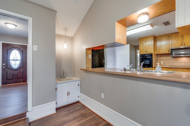 kitchen featuring dark wood-type flooring, decorative light fixtures, sink, and black appliances