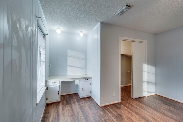 office area with dark hardwood / wood-style floors, built in desk, and a textured ceiling