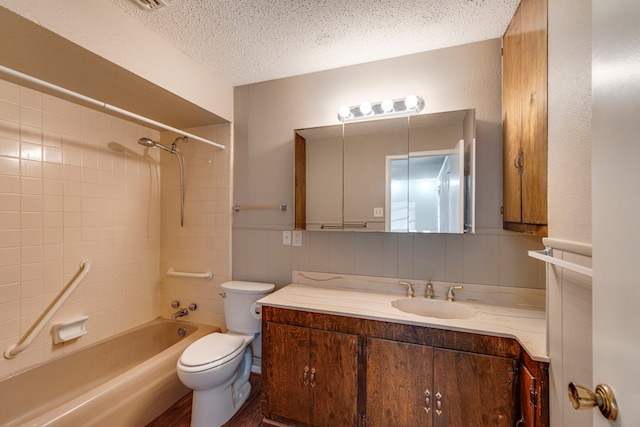 full bathroom featuring vanity, toilet, tiled shower / bath combo, and a textured ceiling