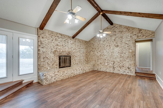 unfurnished living room featuring wood-type flooring, lofted ceiling with beams, a textured ceiling, ceiling fan, and a fireplace