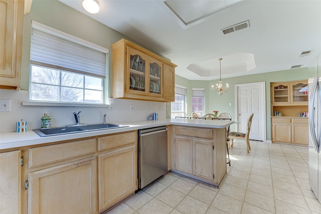 kitchen with pendant lighting, light brown cabinetry, sink, stainless steel dishwasher, and a tray ceiling