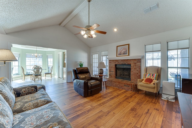 living room featuring hardwood / wood-style floors, a textured ceiling, a fireplace, and beamed ceiling