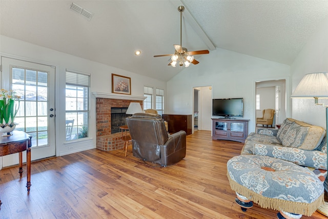 living room featuring a textured ceiling, a wealth of natural light, a fireplace, and light wood-type flooring