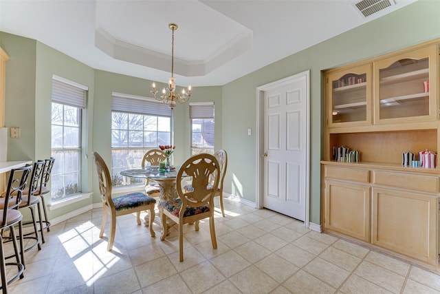 dining area with crown molding, a tray ceiling, a chandelier, and light tile patterned flooring