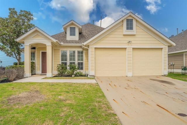 view of front of house with driveway, a shingled roof, a garage, and a front yard