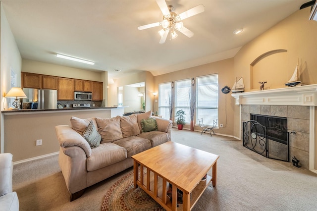 living area with light carpet, ceiling fan, a tile fireplace, and baseboards