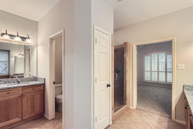 bathroom with tile patterned floors, toilet, an enclosed shower, and vanity