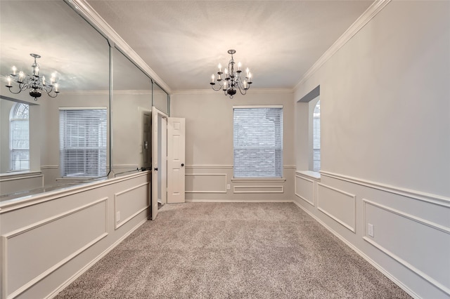 unfurnished room with an inviting chandelier, crown molding, and carpet floors