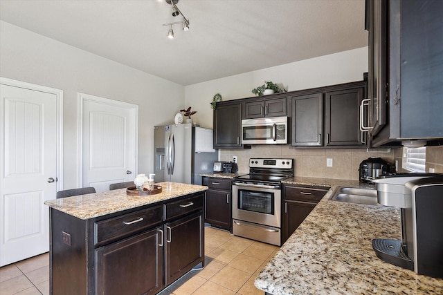 kitchen featuring light tile patterned floors, decorative backsplash, a center island, and appliances with stainless steel finishes