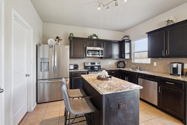 kitchen with sink, a center island, light tile patterned floors, appliances with stainless steel finishes, and backsplash